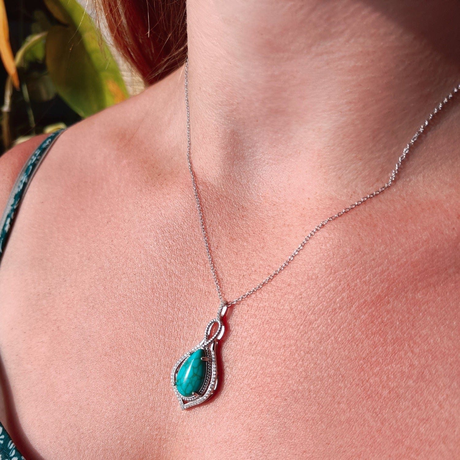 Mermaid's Turquoise Pendant Necklace featuring a turquoise stone set in S925 sterling silver zoomed in on a model with a left side view in natural sunlight