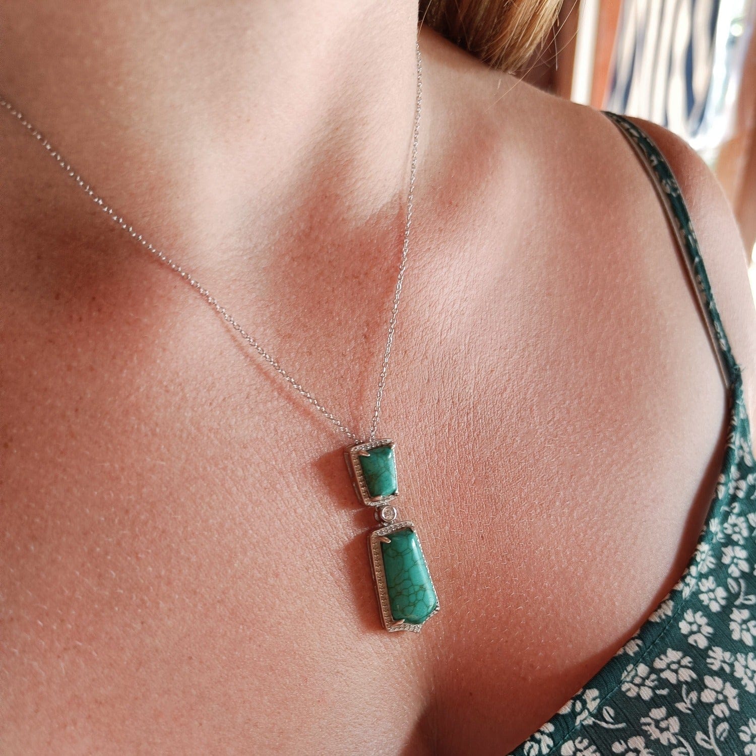 Turquoise Seabed Jewel Necklace featuring a turquoise pendant in a sterling silver setting zoomed in on a model in natural shaded lighting